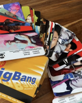 A stack of colorful printed cards or photo strips fanned out on top of a yellow card labeled 'Big Bang' on a wooden surface.